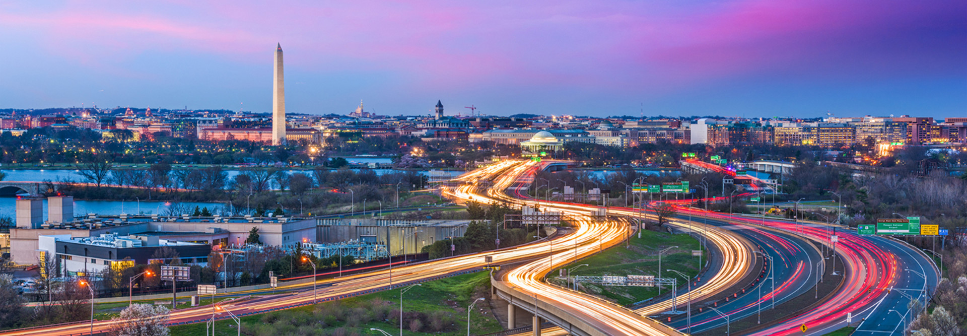 Washington DC skyline at dusk with traffic moving on highways in streams of lights 