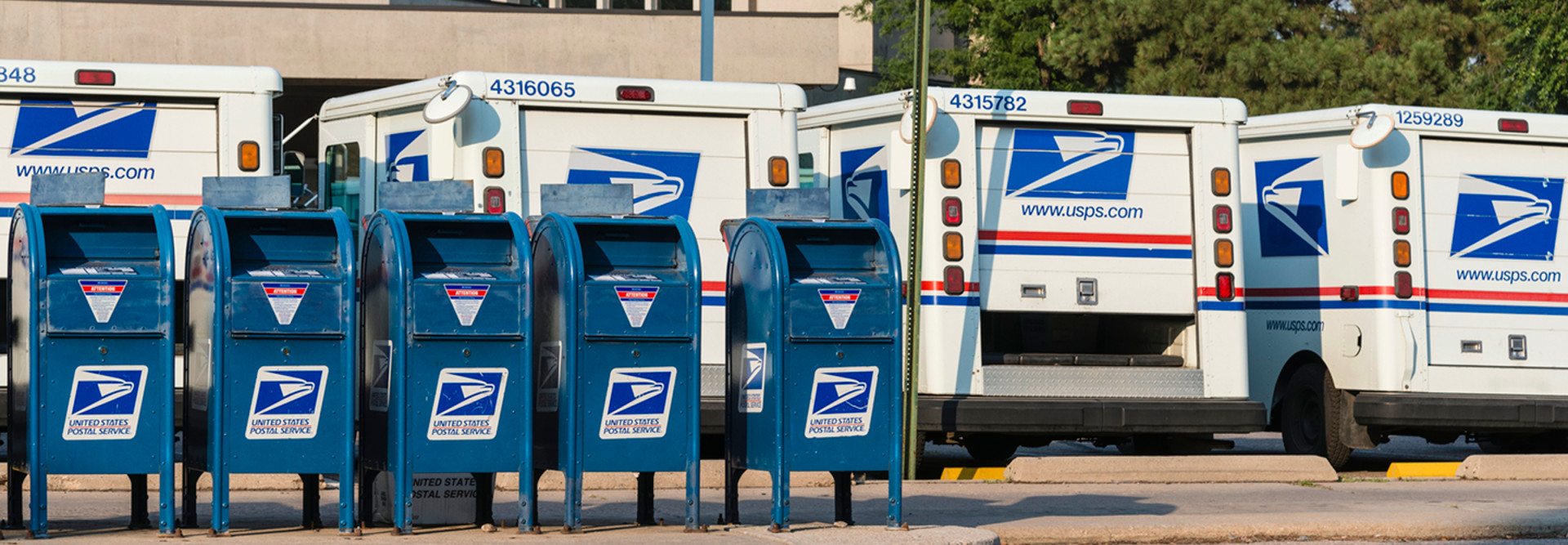 Mailboxes and USPS mail trucks lined up in a parking lot 