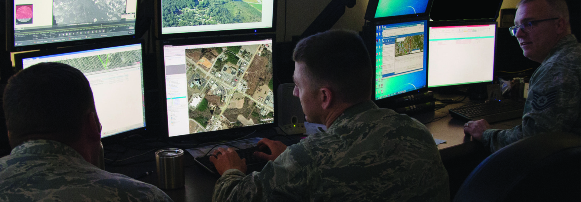 Uniformed Air National Guardsmen analyzing data at computer screens