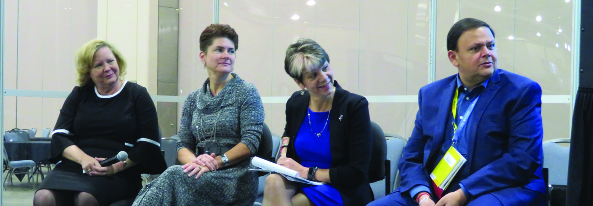 Three women and one man in business clothing reacting to something someone has said