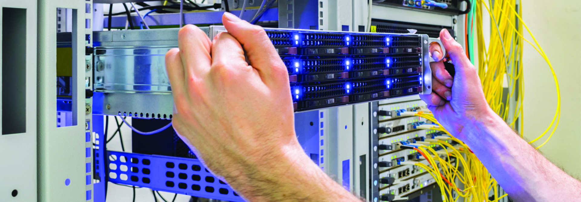 two hands plugging a blade server into a data center