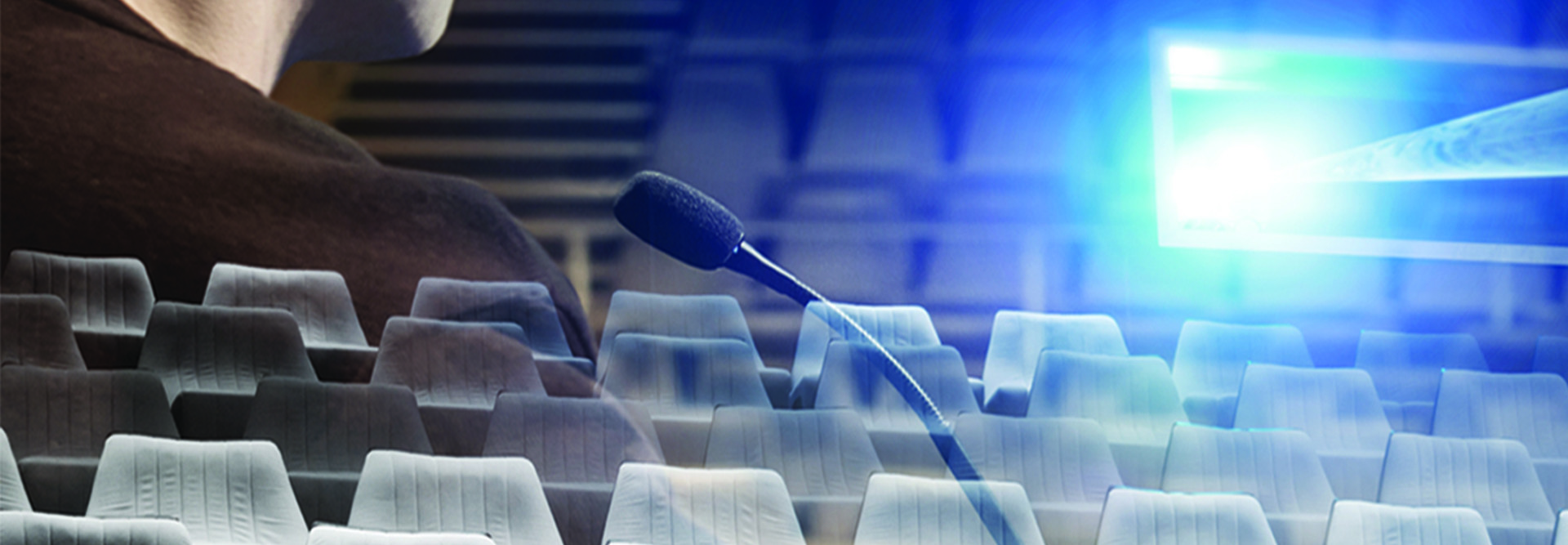 ghostly image of man at microphone in empty auditorium with projector shining light 