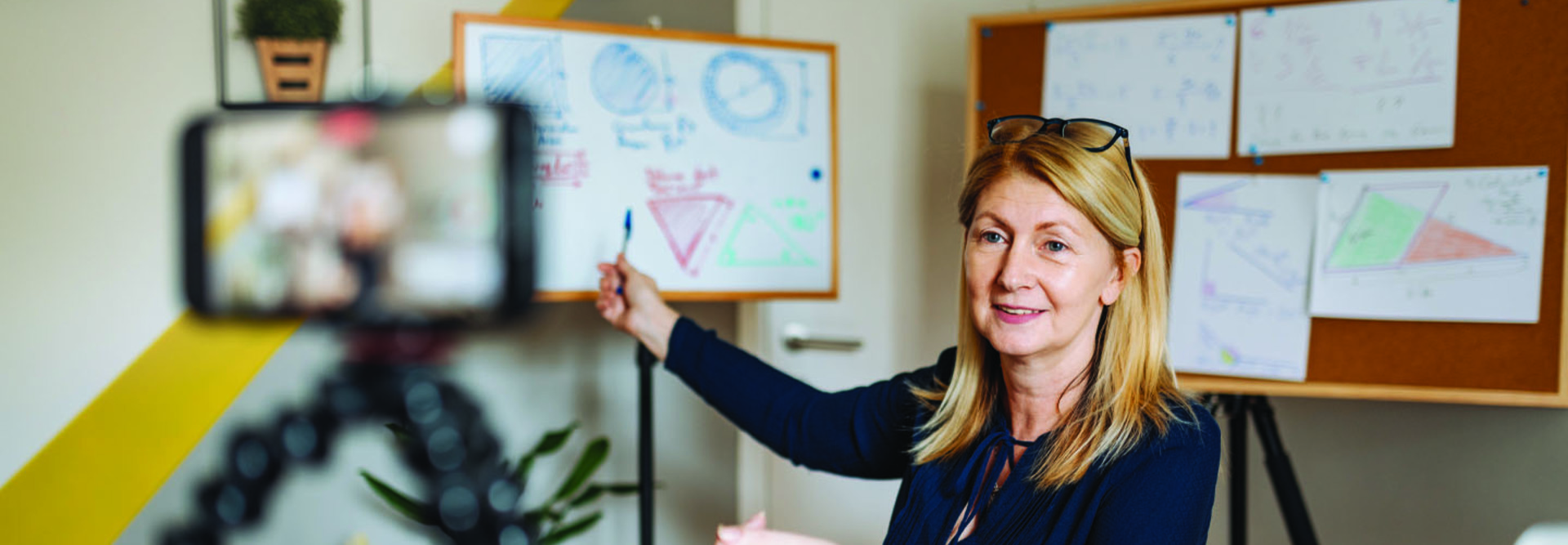 woman pointing at whiteboards and camera