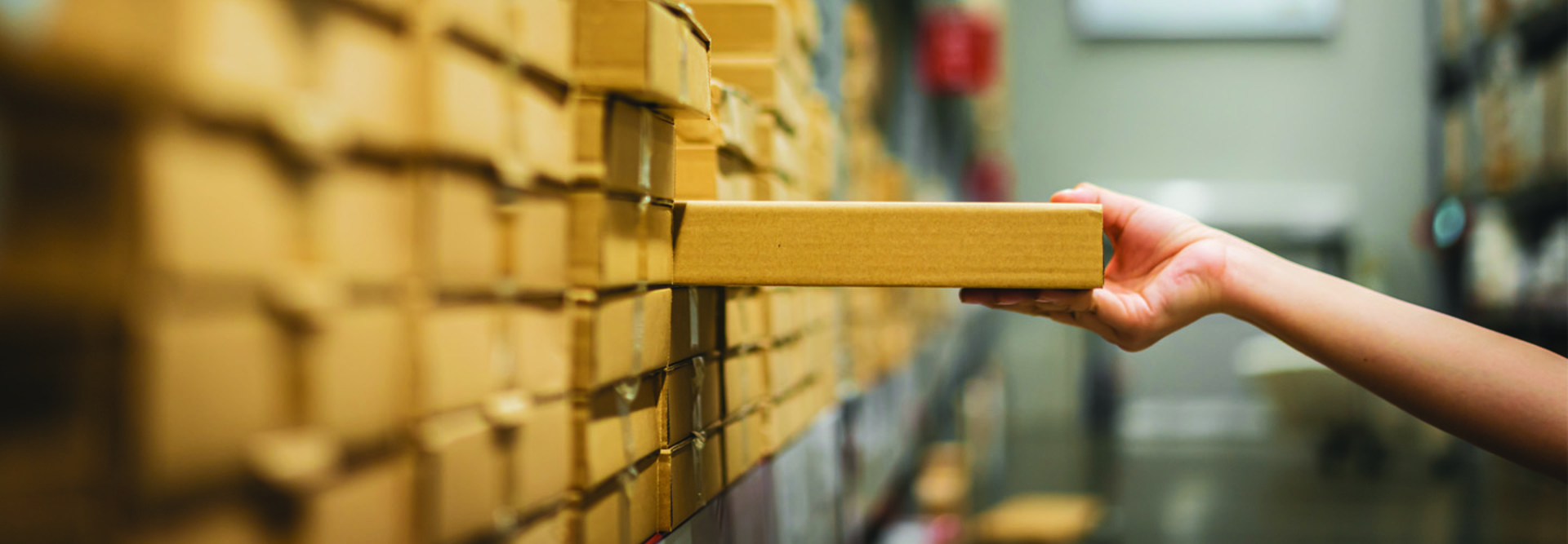 Hand pulling a box off of a warehouse shelf full of boxes