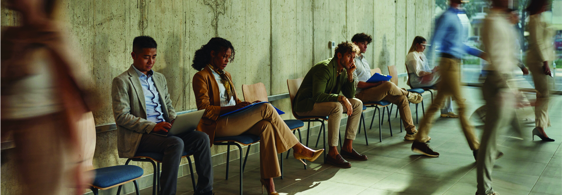 People waiting in chairs against wall