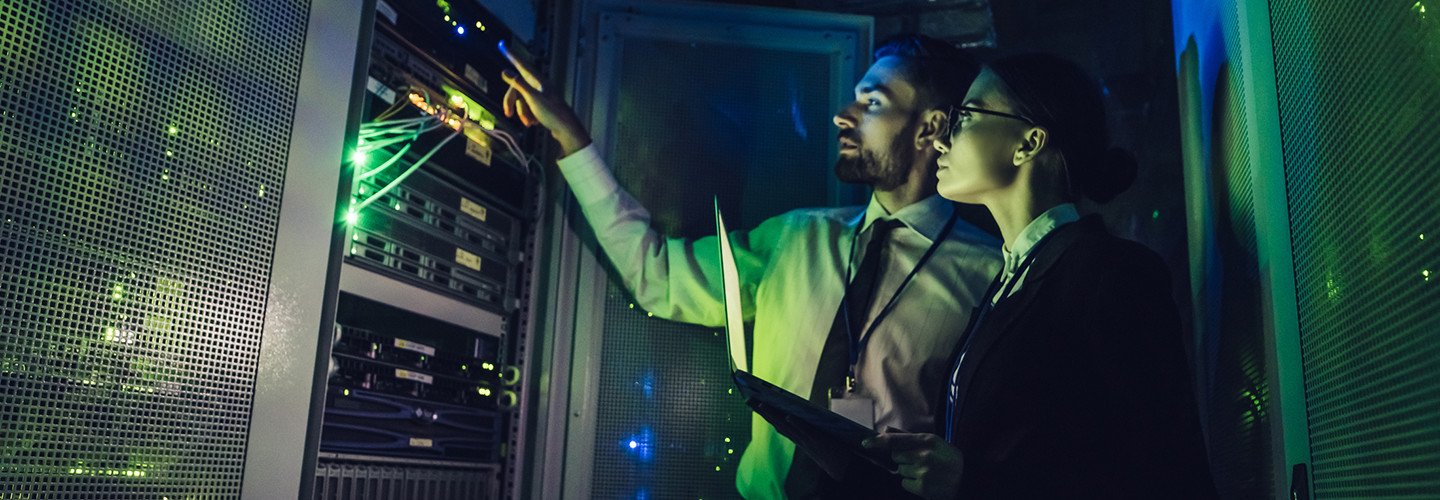 Man and woman checking cybersecurity sensor in a data center 