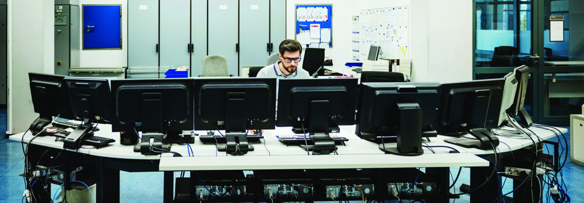 Man sitting behind an array of computer screens