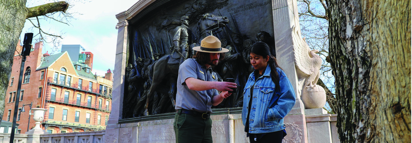park ranger helps tourist with app in front of Glory memorial