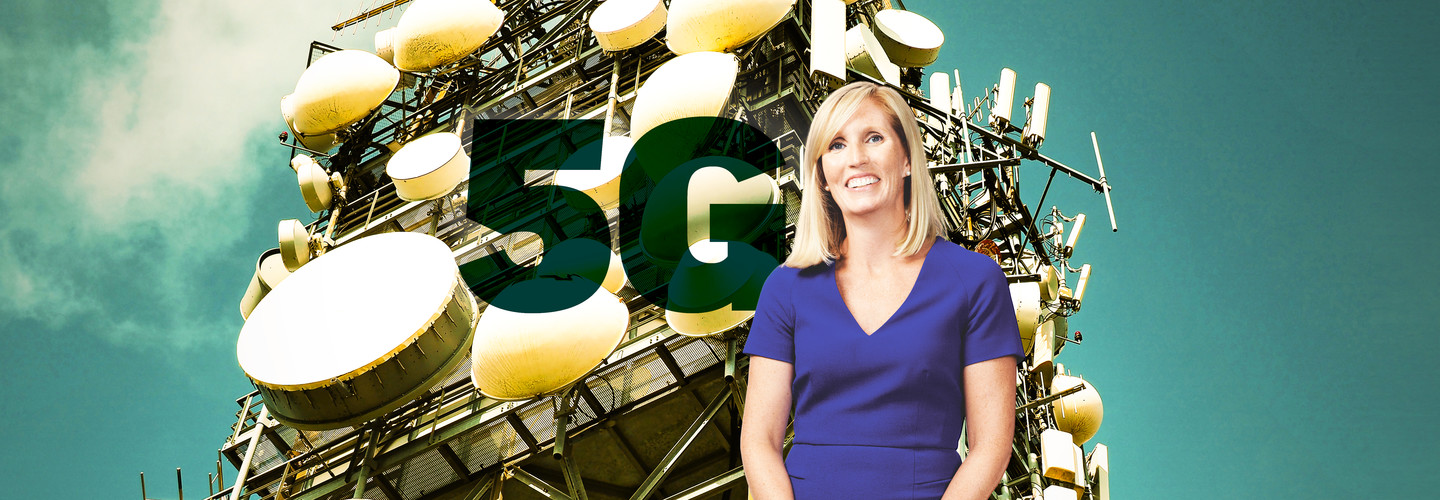 blonde woman in blue dress standing in front of a 5G tower