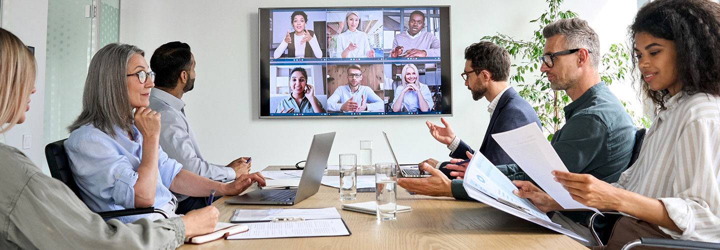 Employees on online conference video call on tv screen in meeting room.