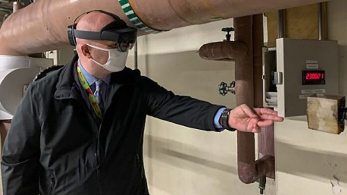 Deputy Facility Manager Jarod Hackett uses the HoloLens headset to look inside the control box during a pre-bid virtual walk-through for the Tokyo Chiller Replacement Project. Photo courtesy of the Bureau of Overseas Buildings Operations