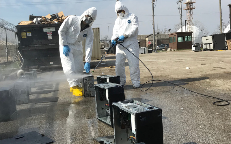Staff Sgt. Christina Ceville and Airman 1st Class Chase Fitz of the 55th Communications Squadron pressure-wash flood-damaged computers and remove sensitive components before turning them over for disposal at Offutt Air Force Base, Nebraska.