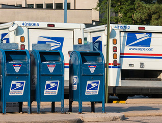 Mailboxes and USPS mail trucks lined up in a parking lot 