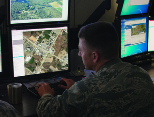 Uniformed Air National Guardsmen analyzing data at computer screens