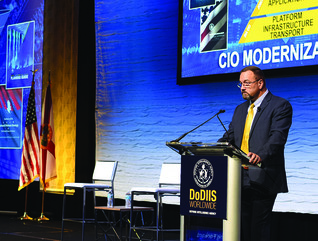Man at podium with slides of pyramids with words