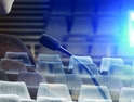 ghostly image of man at microphone in empty auditorium with projector shining light 