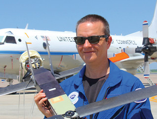 Joe Cione holding a drone and standing in front of a plane