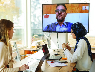 blonde woman and woman in scarf in a meeting with a guy on a screen