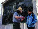 park ranger helps tourist with app in front of Glory memorial