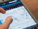 Naval aviator student planning a virtual training flight on a tablet.