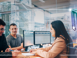 Three employees in front of a computer