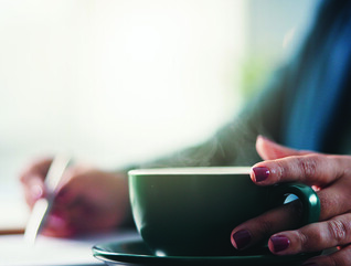 Lady writing with cup of coffee