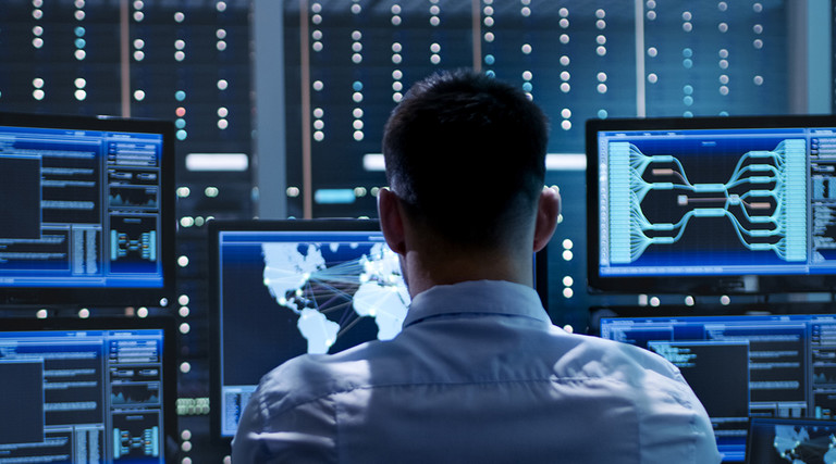 Federal cybersecurity worker sitting behind many monitors 
