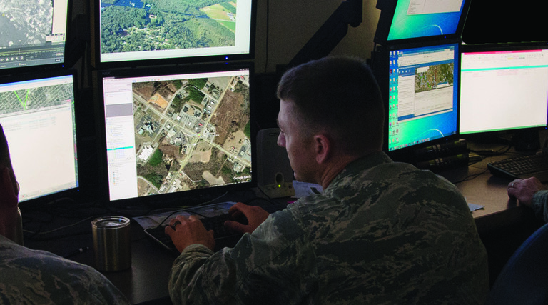 Uniformed Air National Guardsmen analyzing data at computer screens