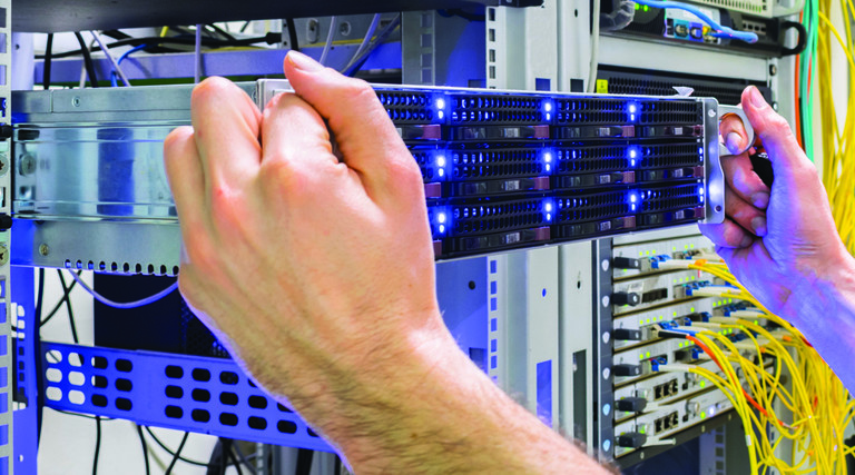 two hands plugging a blade server into a data center