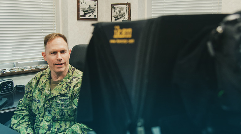 man in camo uniform talking to a TV camera