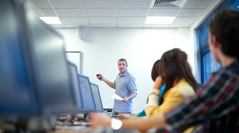 man teaching class sitting in front of computers