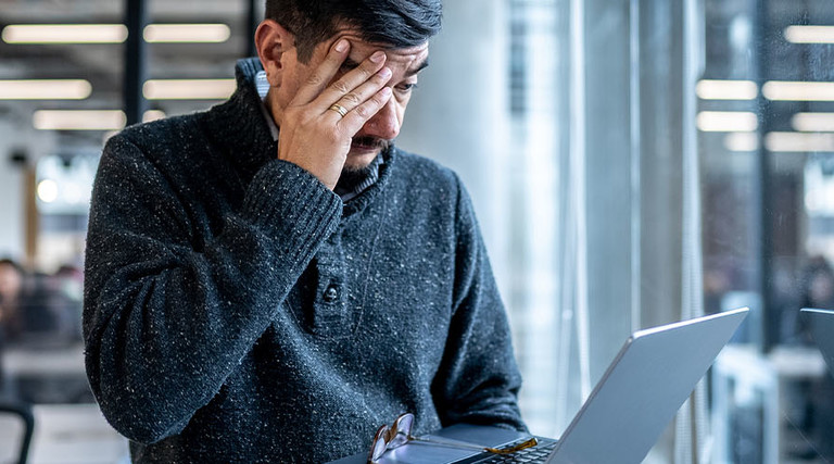Worried man looking at his laptop in the office