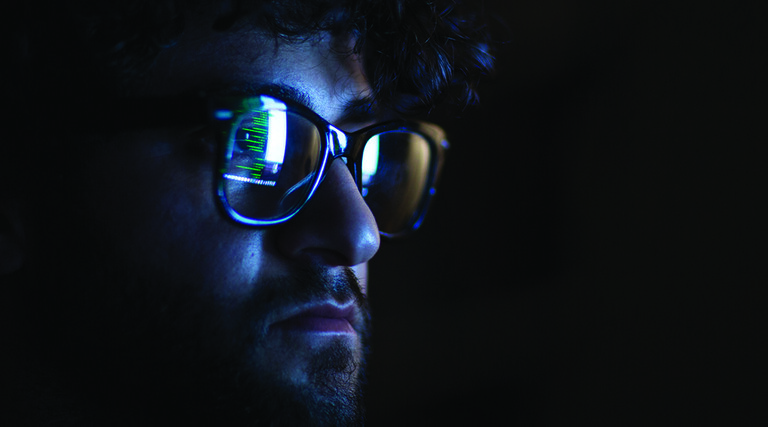 Computer code reflected on the glasses on a man's face