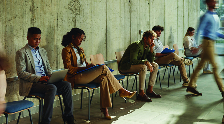 People waiting in chairs against wall