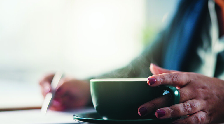 Lady writing with cup of coffee