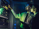 Man and woman checking cybersecurity sensor in a data center 