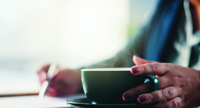 Lady writing with cup of coffee