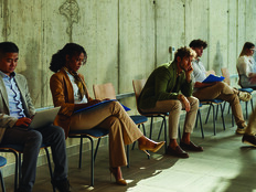 People waiting in chairs against wall
