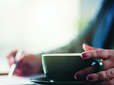 Lady writing with cup of coffee
